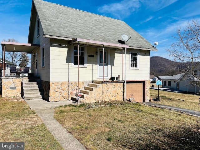 view of front facade featuring an attached garage, a shingled roof, and a front yard