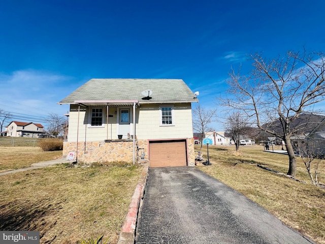 bungalow with an attached garage, aphalt driveway, and a front lawn