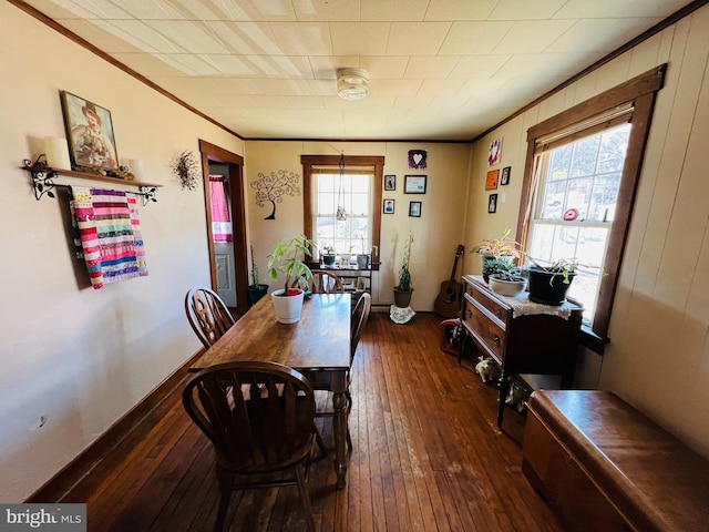 dining room featuring ornamental molding, dark wood finished floors, and baseboards