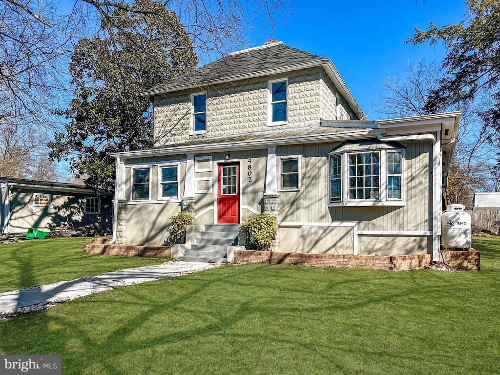 american foursquare style home featuring a front lawn and entry steps