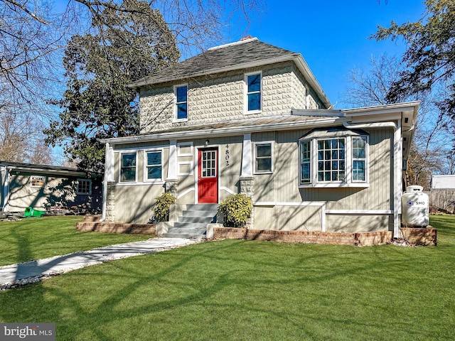 american foursquare style home featuring a front lawn and entry steps