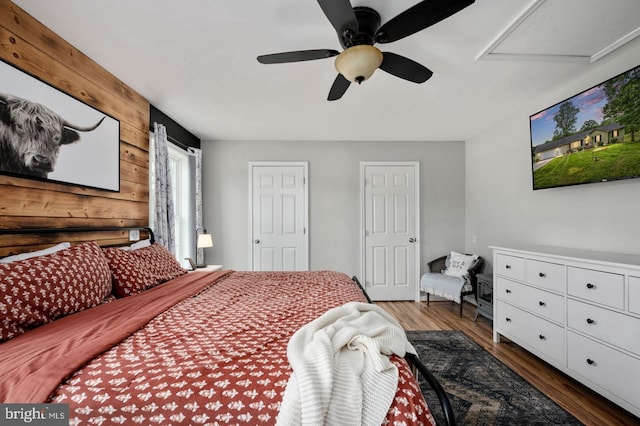 bedroom featuring wood walls, a ceiling fan, and wood finished floors