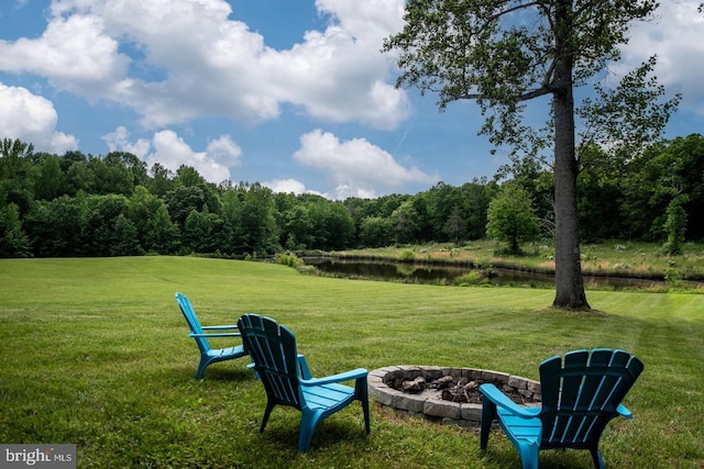 view of yard with a water view, a fire pit, and a forest view