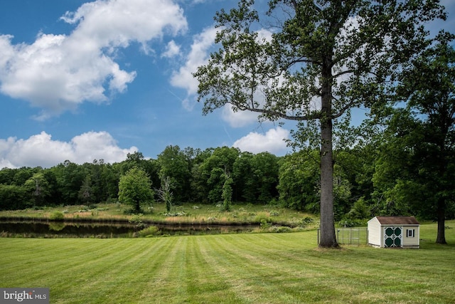 view of yard featuring a shed, a water view, and an outdoor structure