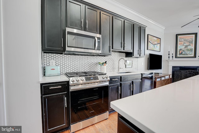 kitchen with stainless steel appliances, a sink, light countertops, ornamental molding, and decorative backsplash