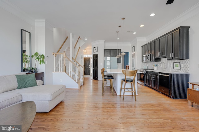 kitchen with appliances with stainless steel finishes, light wood-type flooring, open floor plan, and a kitchen bar