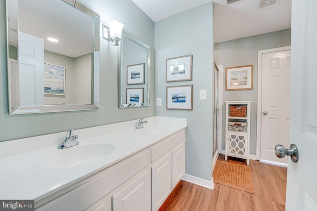 full bath featuring double vanity, wood finished floors, a sink, and visible vents