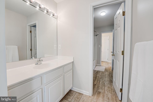 full bath with wood tiled floor, baseboards, walk in shower, and vanity