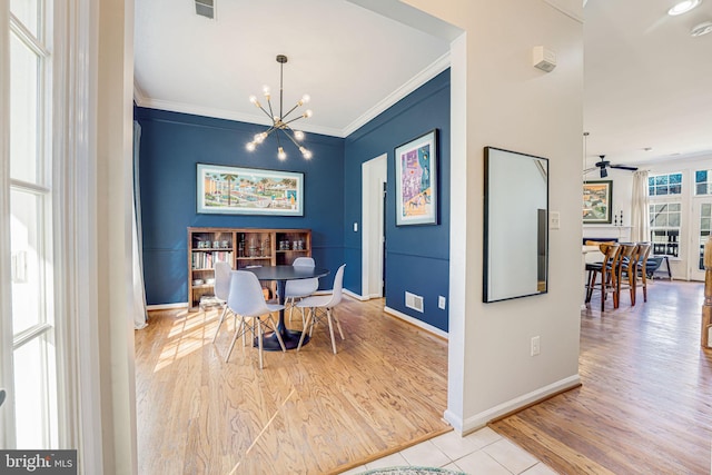 dining room with ceiling fan with notable chandelier, baseboards, crown molding, and wood finished floors