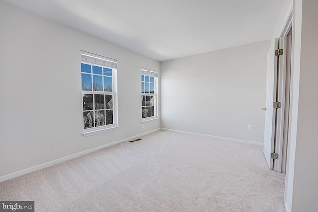 empty room with carpet, visible vents, and baseboards