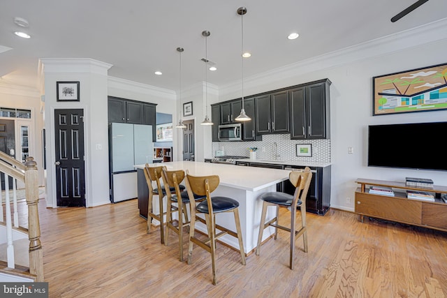 kitchen with a breakfast bar, a center island, stainless steel appliances, light countertops, and dark cabinets