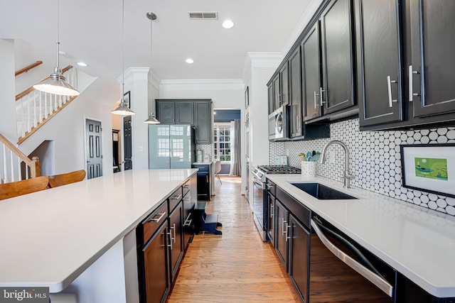 kitchen with stainless steel appliances, light countertops, a sink, and backsplash