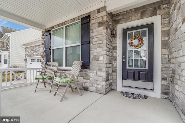 entrance to property featuring a porch and stone siding