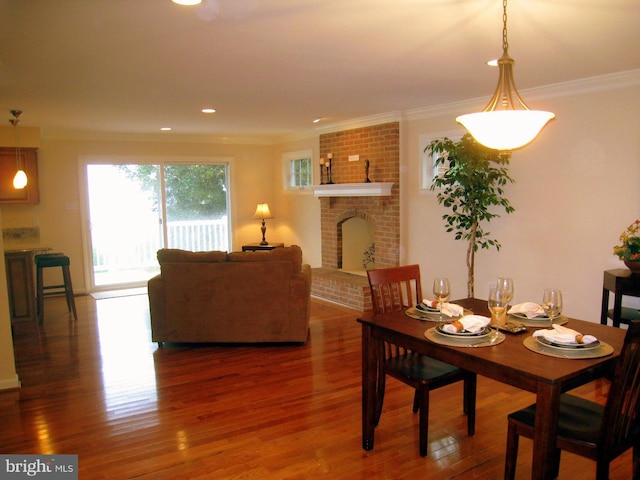 dining space featuring ornamental molding, recessed lighting, a fireplace, and wood finished floors