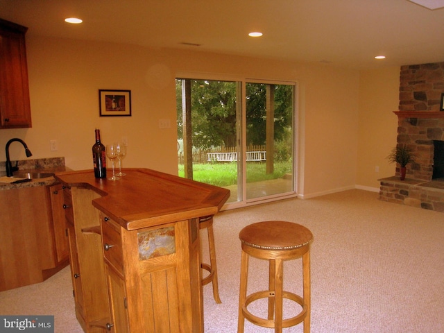 kitchen featuring recessed lighting, a fireplace, a sink, and light colored carpet