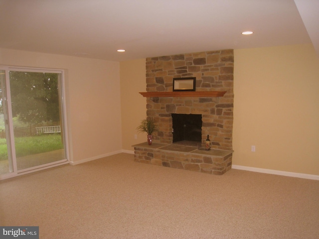 unfurnished living room with carpet, a stone fireplace, baseboards, and recessed lighting