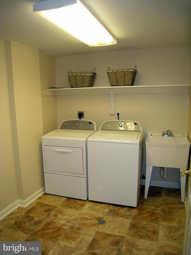 laundry area with laundry area, baseboards, washer and clothes dryer, and a sink