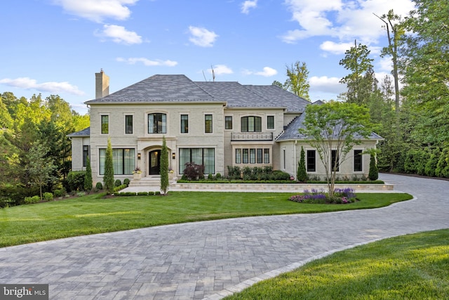 view of front of property featuring a chimney, a front lawn, and a high end roof