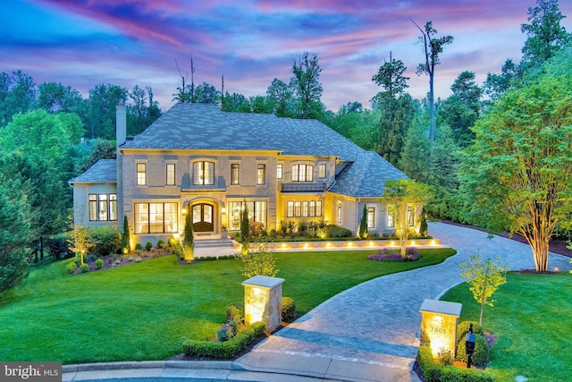 view of front facade featuring a yard, decorative driveway, and a chimney