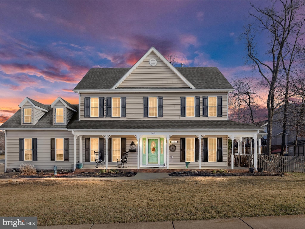 view of front facade featuring a porch, a front yard, and a shingled roof
