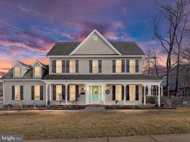 view of front facade featuring a porch, a front yard, and a shingled roof