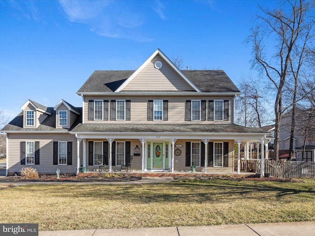 view of front of property featuring covered porch, fence, and a front lawn