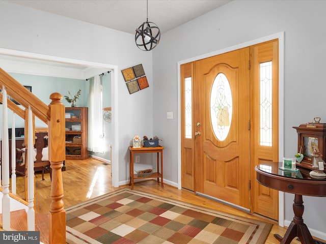 entryway featuring a notable chandelier, stairway, baseboards, and light wood-style floors