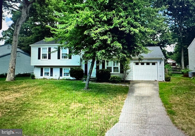 tri-level home with a garage, concrete driveway, and a front lawn