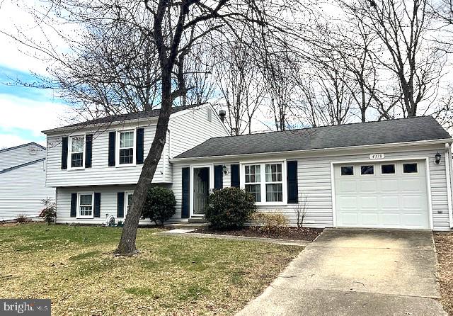 tri-level home featuring a garage, concrete driveway, and a front yard