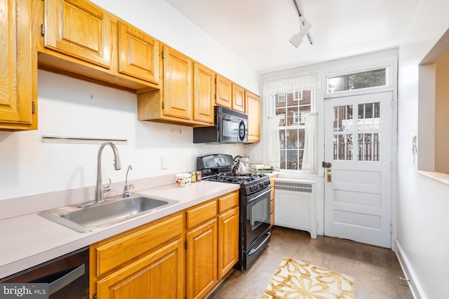 kitchen with radiator, rail lighting, light countertops, black appliances, and a sink