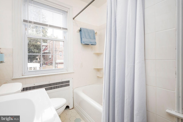 full bathroom featuring toilet, tile walls, tile patterned floors, radiator, and shower / bath combo