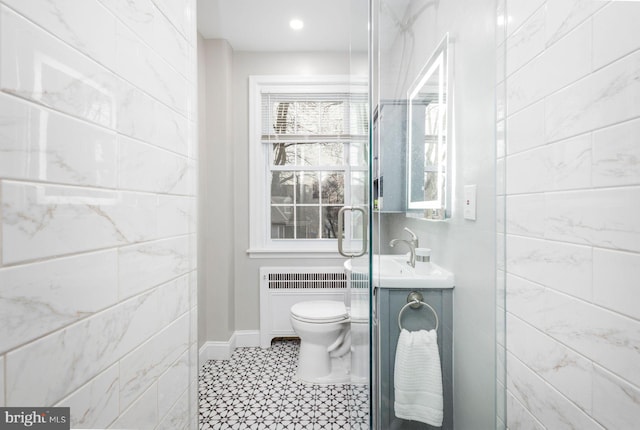 bathroom featuring radiator, baseboards, a sink, and toilet