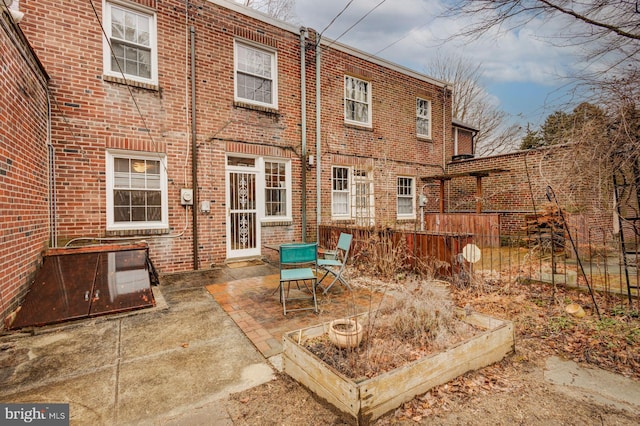 rear view of house with fence, a patio, and brick siding