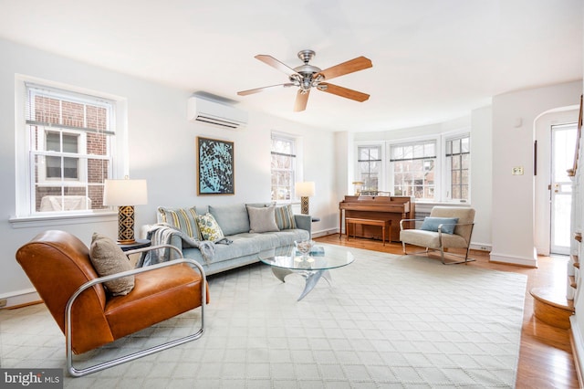 living room with a wall unit AC, a healthy amount of sunlight, arched walkways, and wood finished floors