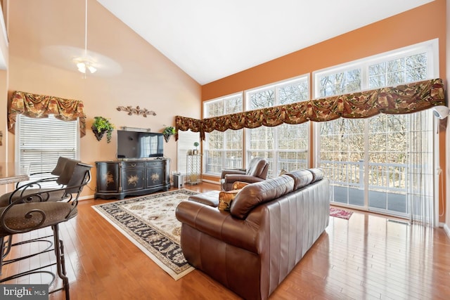 living room with high vaulted ceiling, wood-type flooring, baseboards, and a ceiling fan