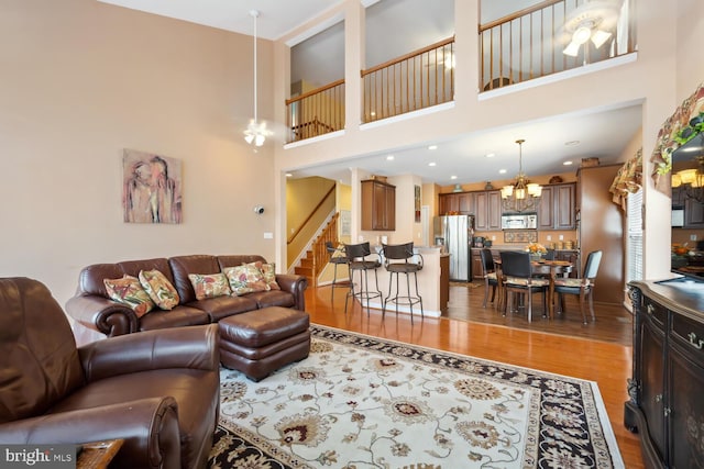 living room with light wood-type flooring, a notable chandelier, and stairs