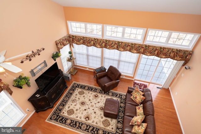 living room featuring plenty of natural light, wood finished floors, a ceiling fan, and baseboards