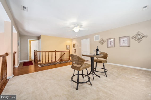 living area featuring carpet, visible vents, and an upstairs landing