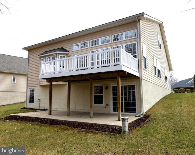 rear view of property featuring a patio area, a lawn, and a wooden deck