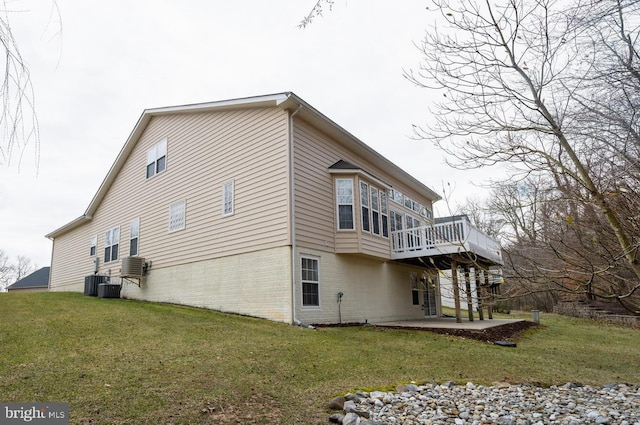 view of side of home featuring a yard, a patio area, brick siding, and a wooden deck