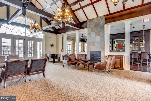 living room featuring a chandelier, french doors, a fireplace, and ornate columns