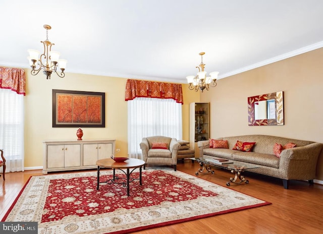 living area with baseboards, crown molding, a chandelier, and wood finished floors