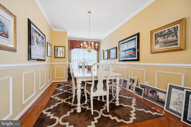 dining area with crown molding, wood finished floors, and a decorative wall