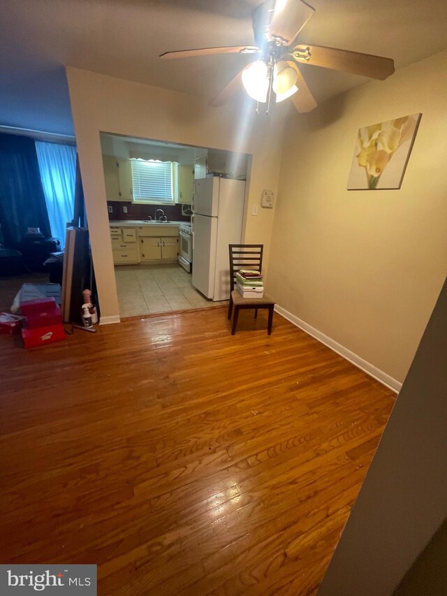 hallway with light wood-style floors, baseboards, and a sink