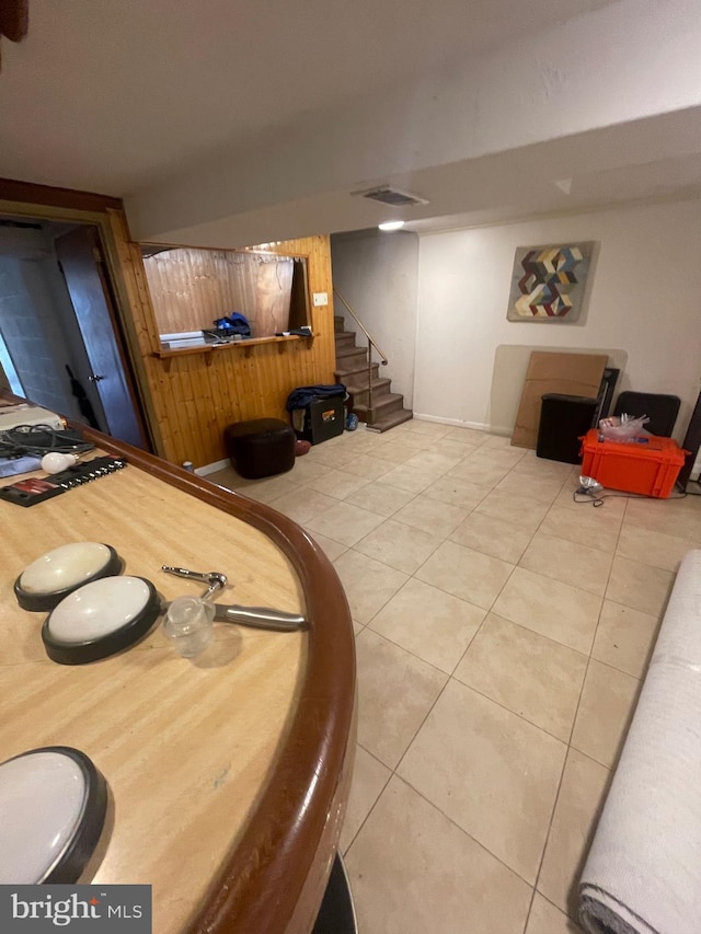 tiled dining room featuring stairway, wood walls, and baseboards