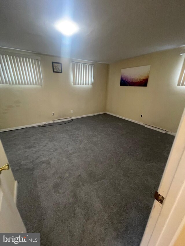 spare room with baseboards and dark carpet