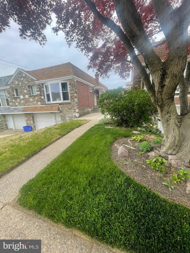 view of side of home with a lawn, an attached garage, a chimney, and stone siding