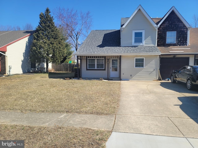 traditional home with a front lawn, fence, roof with shingles, concrete driveway, and an attached garage