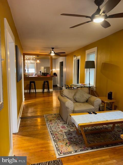 living area featuring ceiling fan, wood finished floors, and baseboards