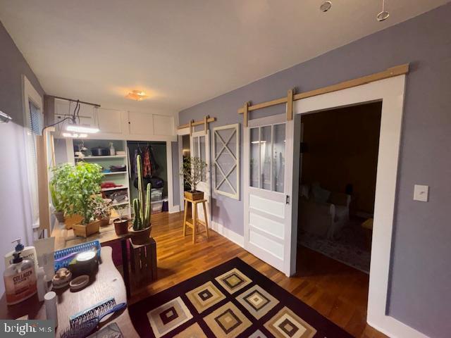 hallway with a barn door and wood finished floors